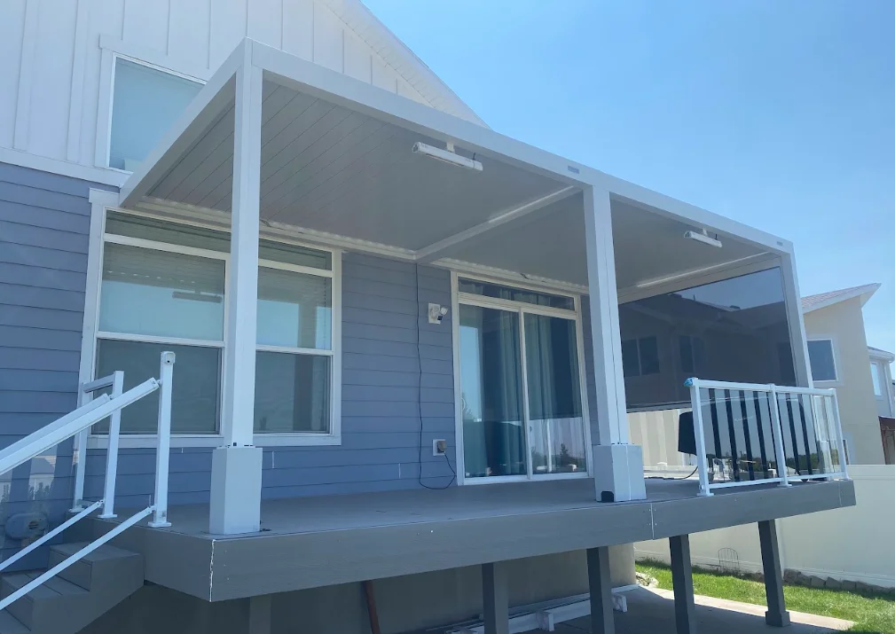 White aluminum pergola with retractable shade over elevated deck with windows and railings