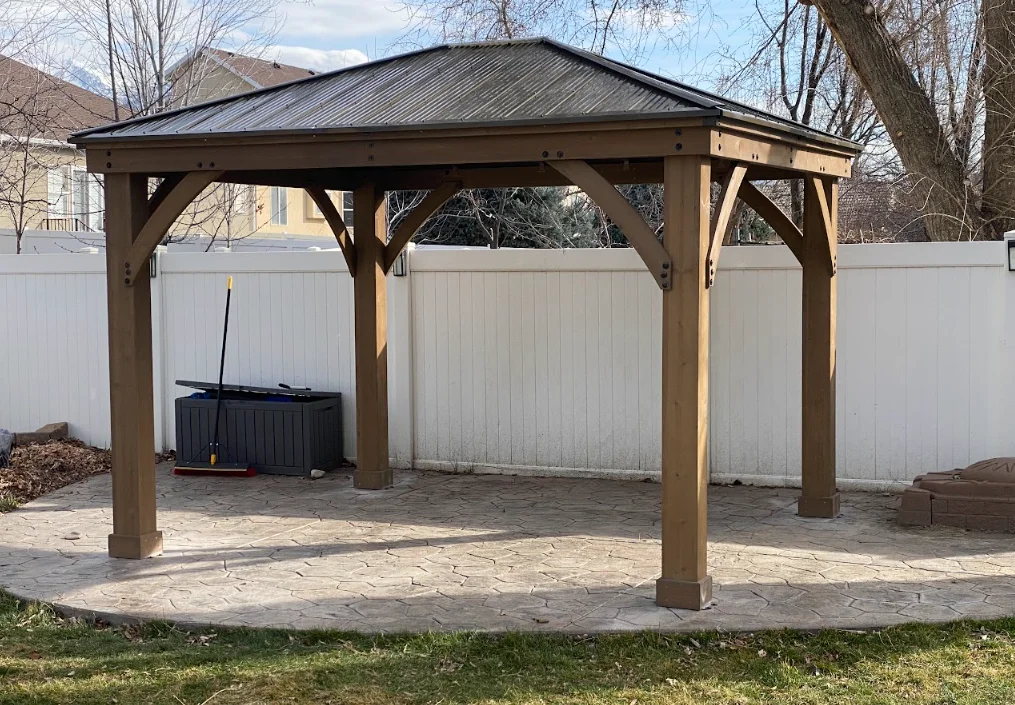 Wooden gazebo with timber frame and metal roof over paver patio