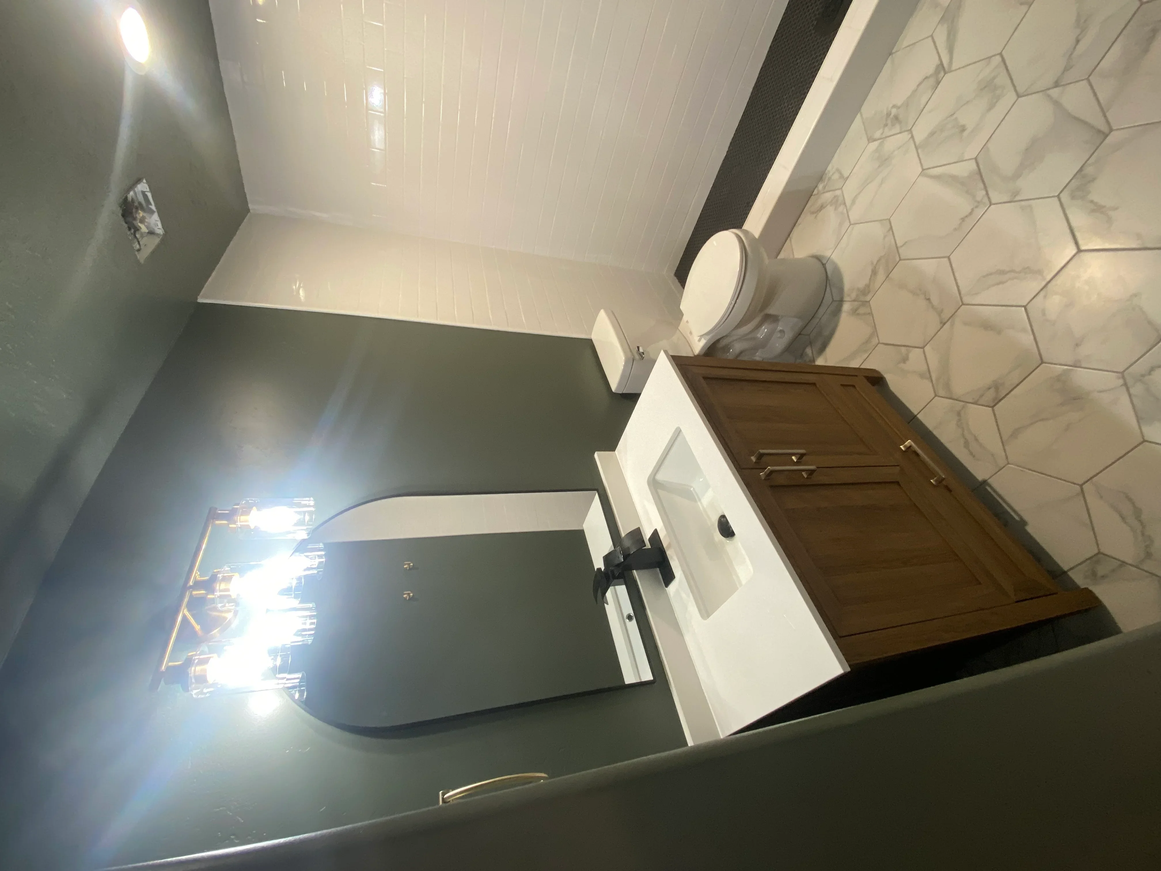Bathroom with hexagon marble floor tile, white subway wall tile, and white vanity with fixtures