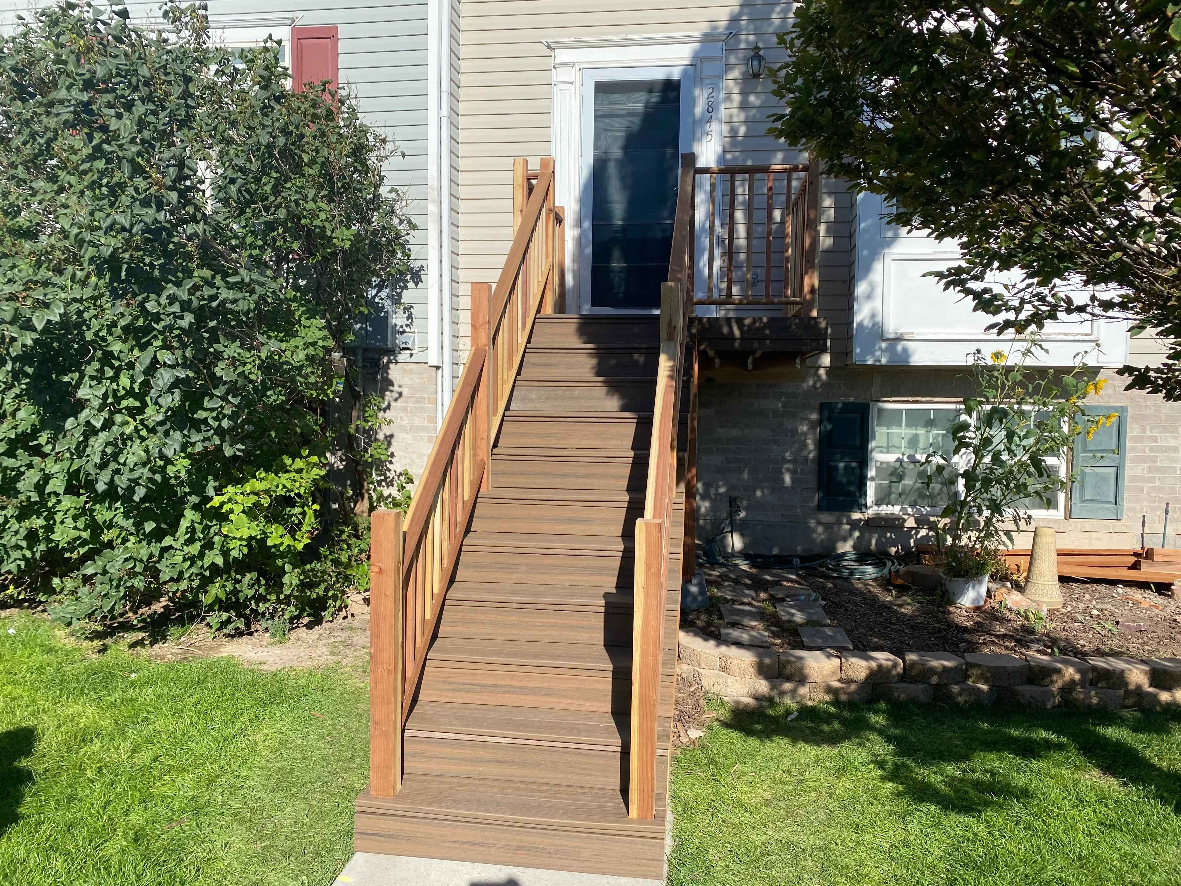 Composite deck stairs with wood railings and balusters leading to upper entrance