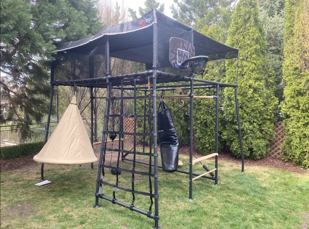 Black metal trampoline canopy with retractable shade cover and basketball hoop mounted on frame