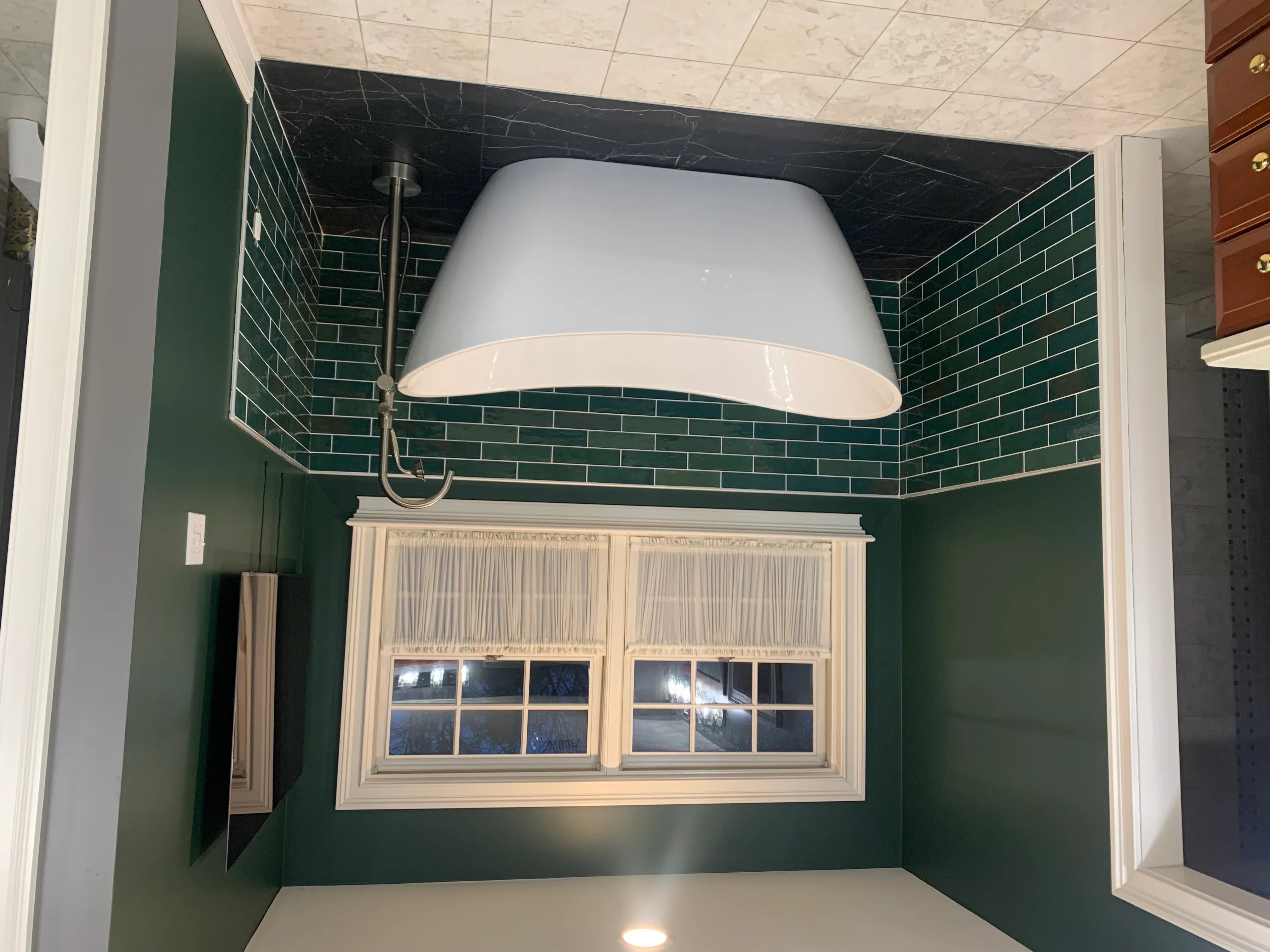 Green subway tile bathroom walls with black marble ceiling and white trim