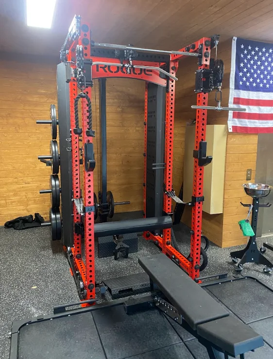 Red and black power rack with weight plates installed on rubber gym flooring