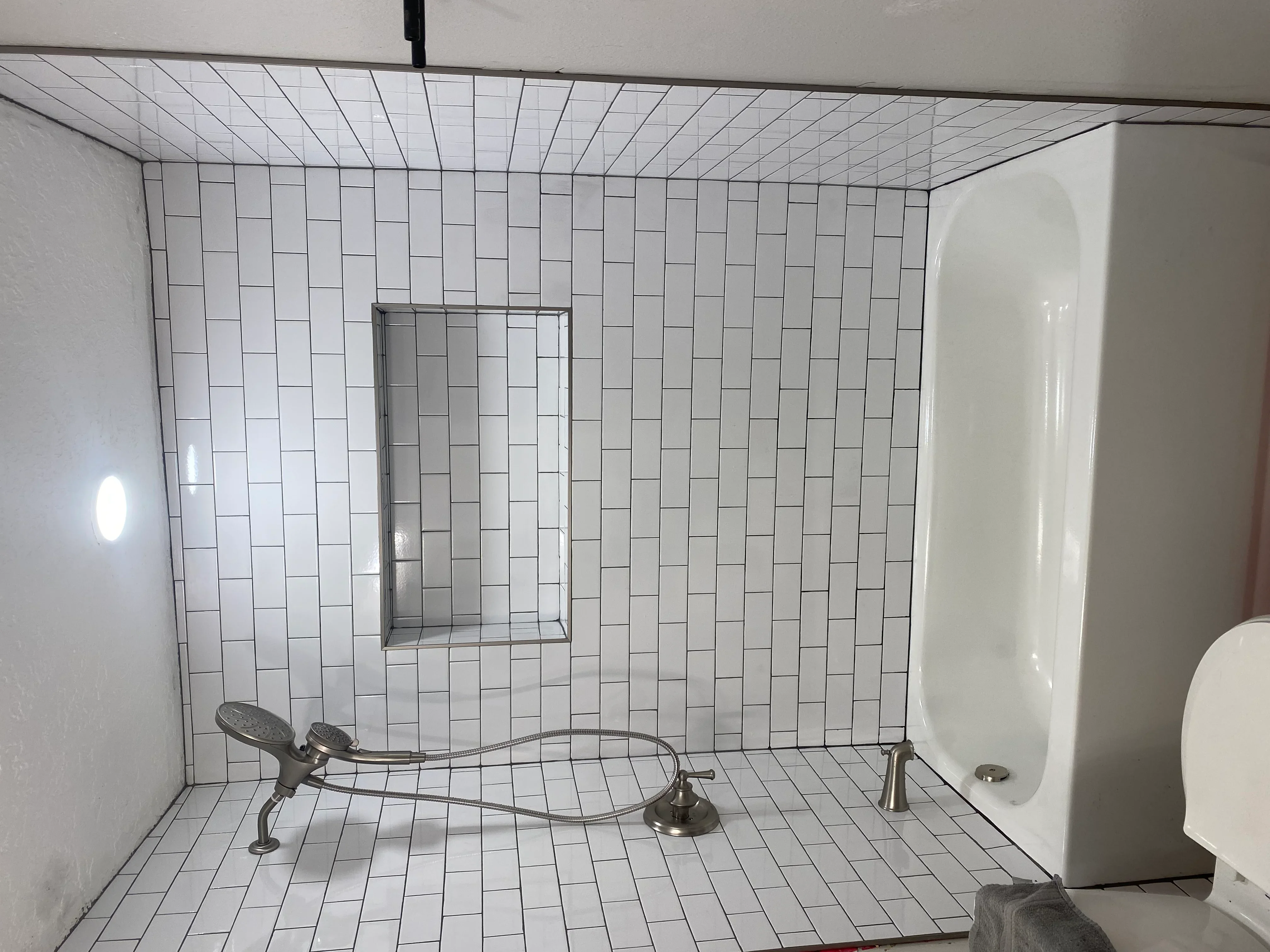 White subway tile shower with running bond pattern, recessed niche, and brushed nickel fixtures