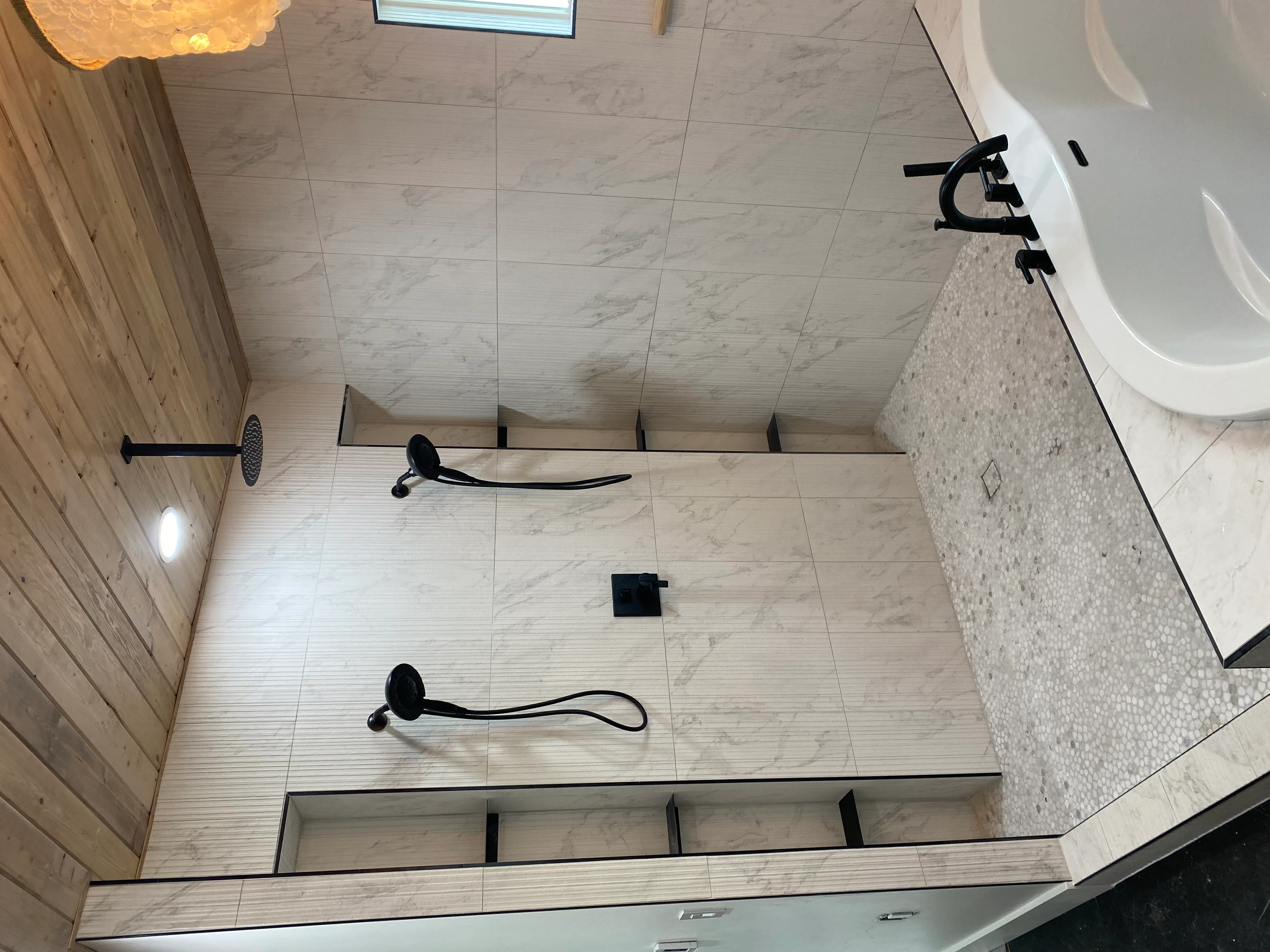 Marble-look porcelain tile bathroom floor with black fixtures and rainfall showerhead installation