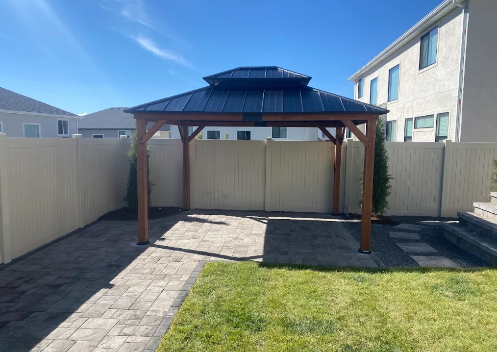 Wooden gazebo with dark metal roof and timber frame on paver patio