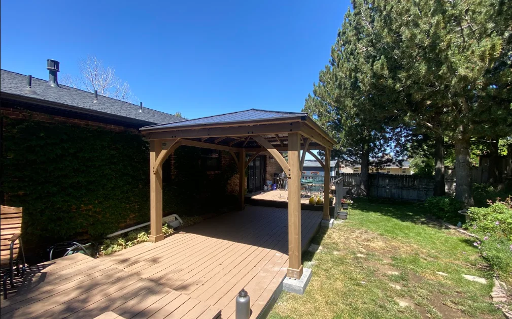 Wooden pergola with timber posts and beams over composite deck in backyard setting