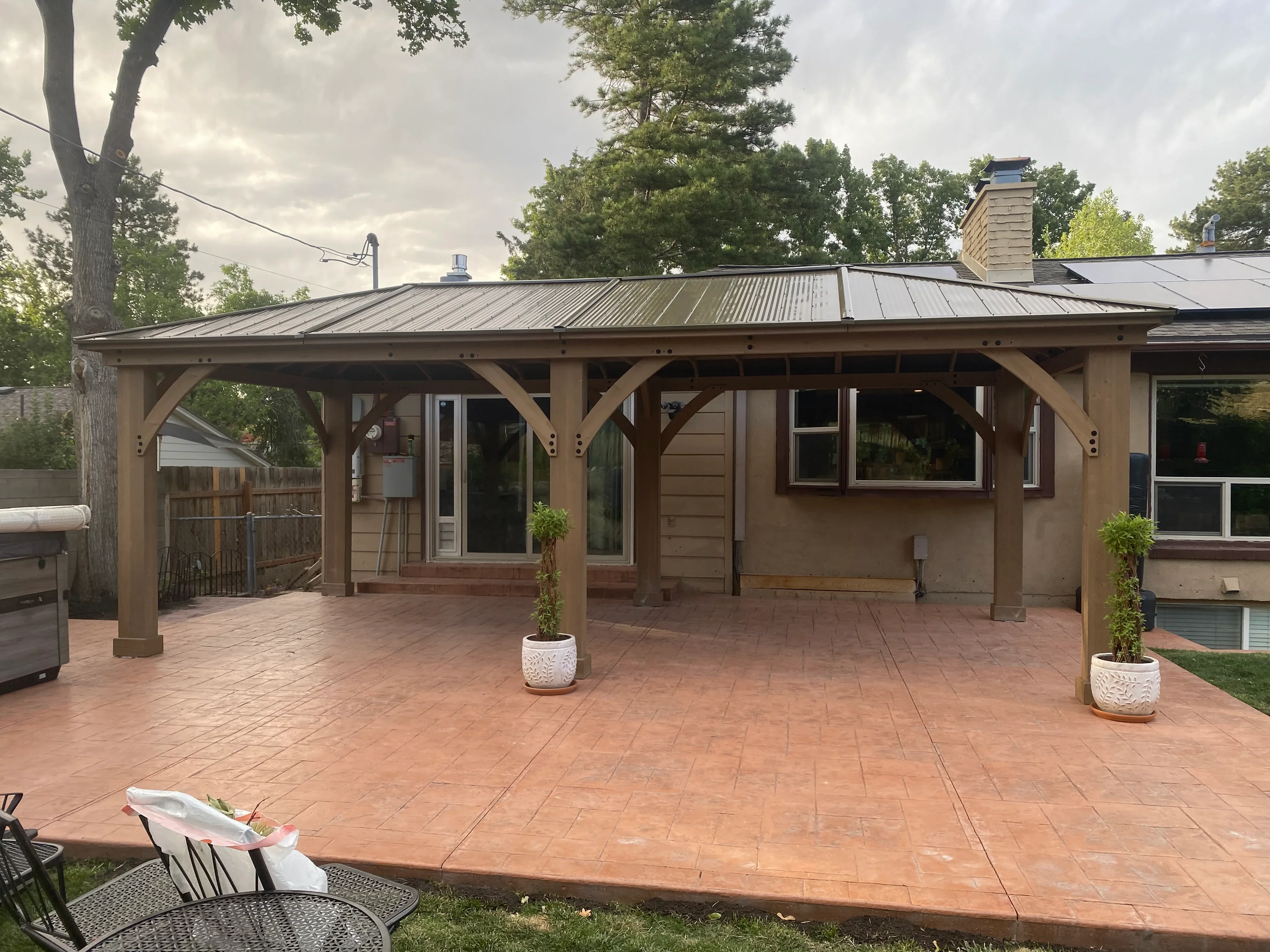 Timber-frame covered patio with standing-seam metal roof and concrete patio surface