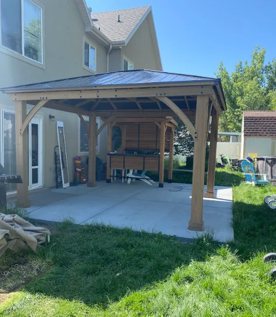 Timber frame covered patio with blue metal roof and concrete pad attached to house