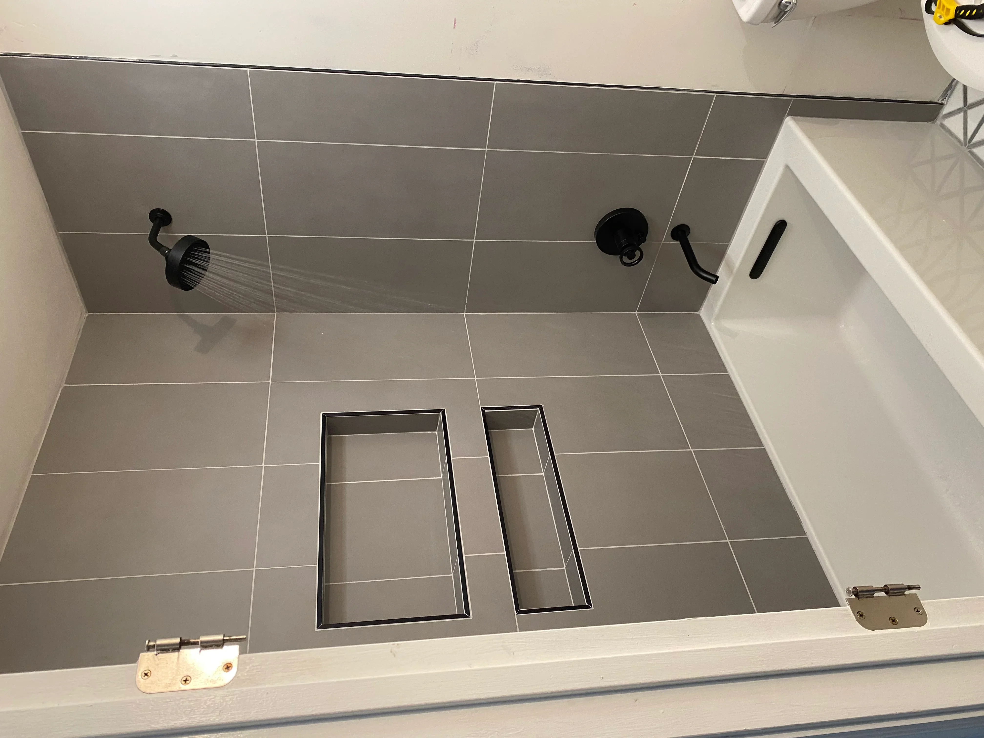 Gray ceramic tile shower with two recessed niches and black fixtures