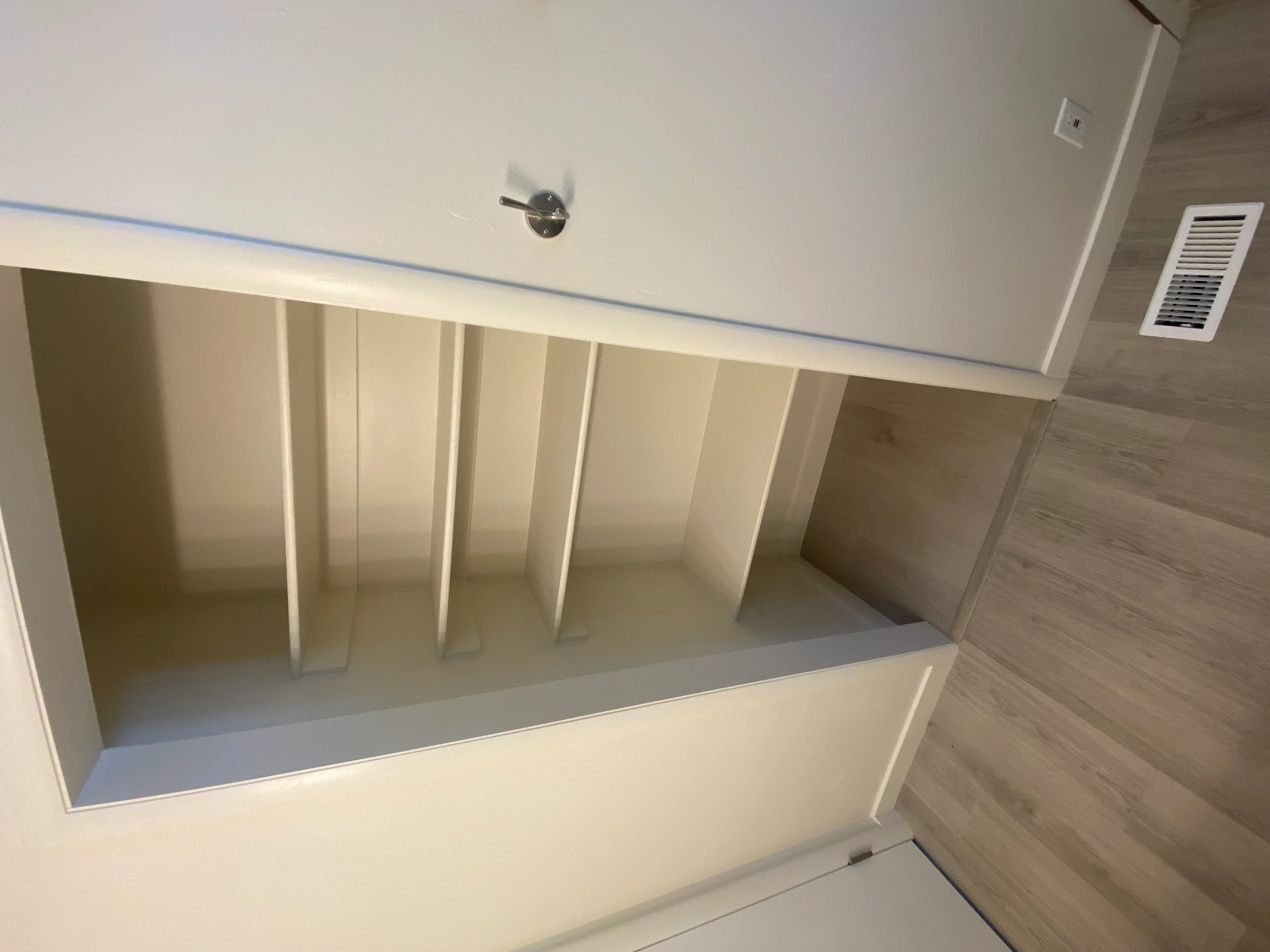 White built-in shelving with vertical dividers and gray countertop, drywall and trim work