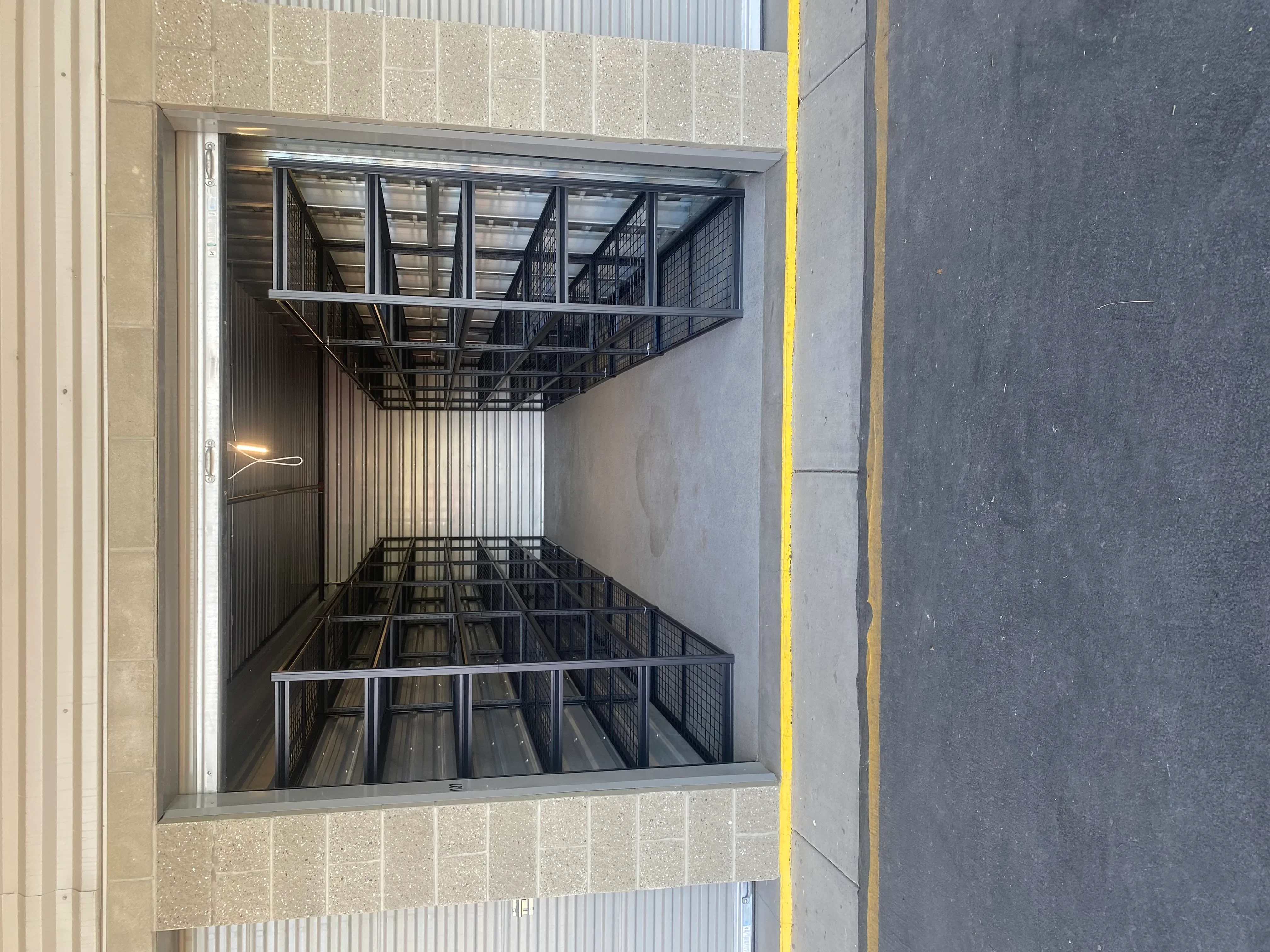 Three-tier metal shelving with mesh panels and steel frame in concrete utility room