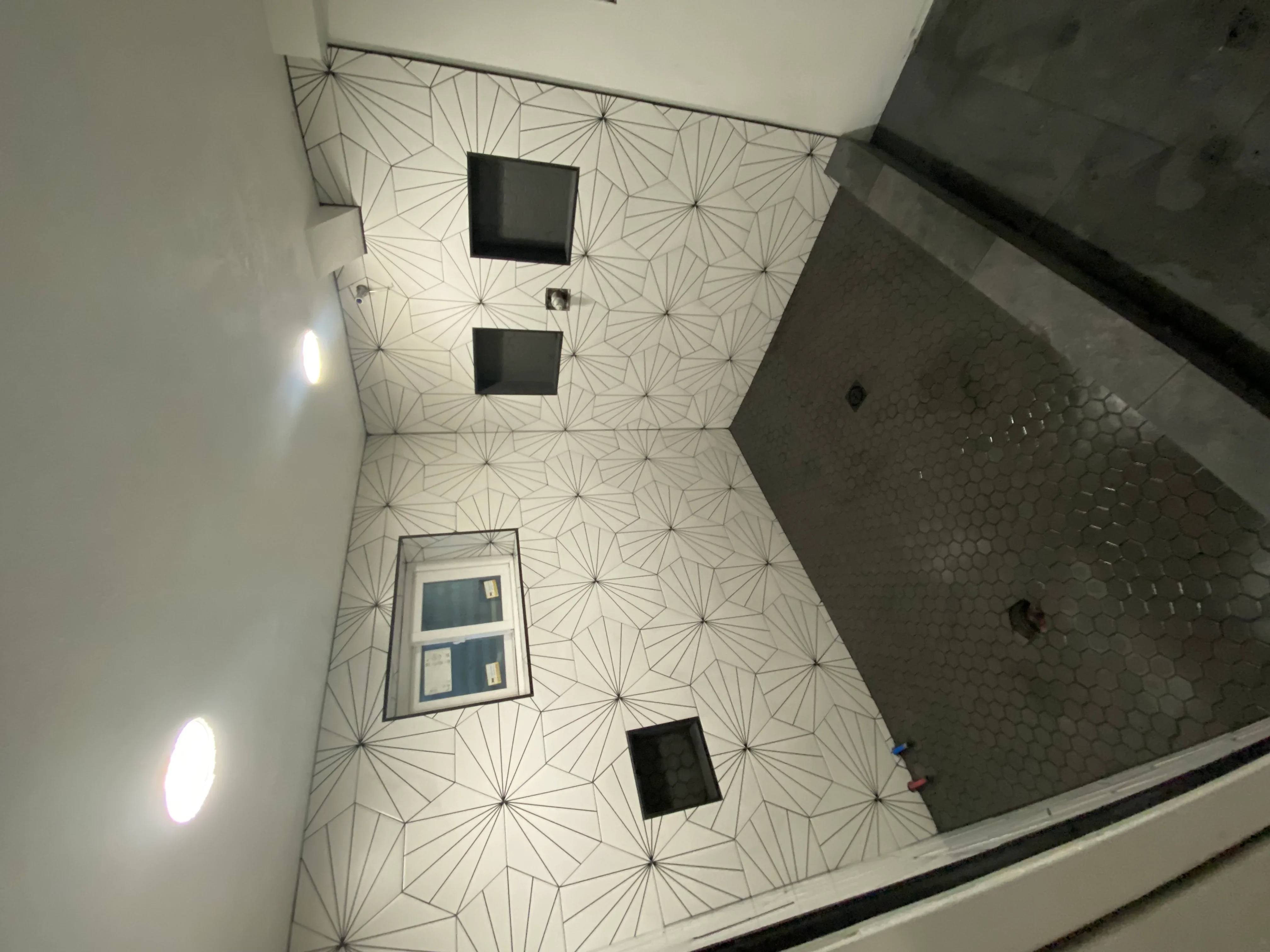 Geometric patterned ceiling tiles with recessed lighting and electrical boxes installed