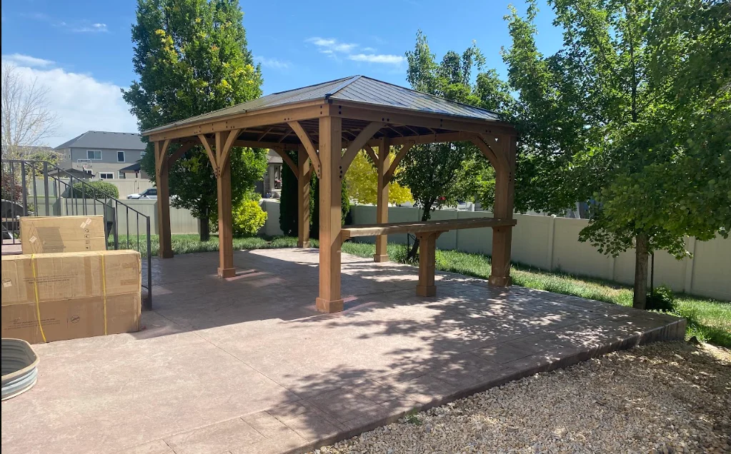 Cedar gazebo with metal roof on stamped concrete patio in backyard