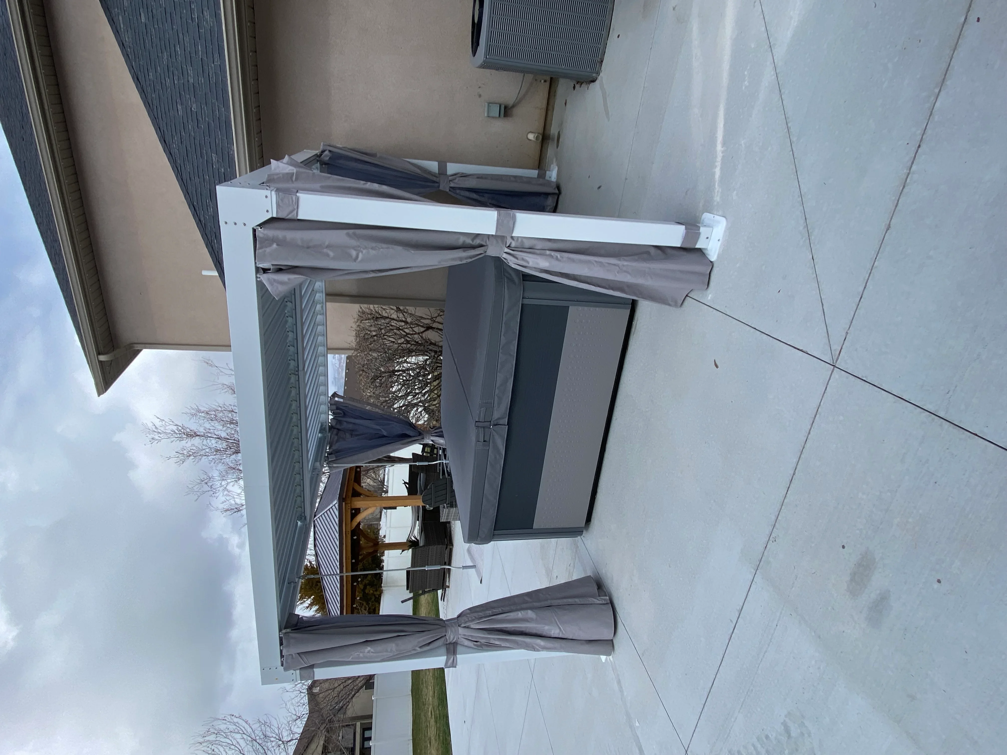 Motorized retractable awning with gray fabric and white aluminum frame installed over patio