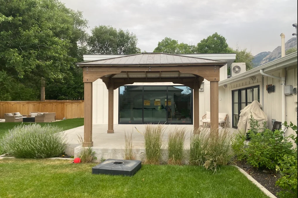 Wooden pergola with retractable shade over concrete patio and glass doors