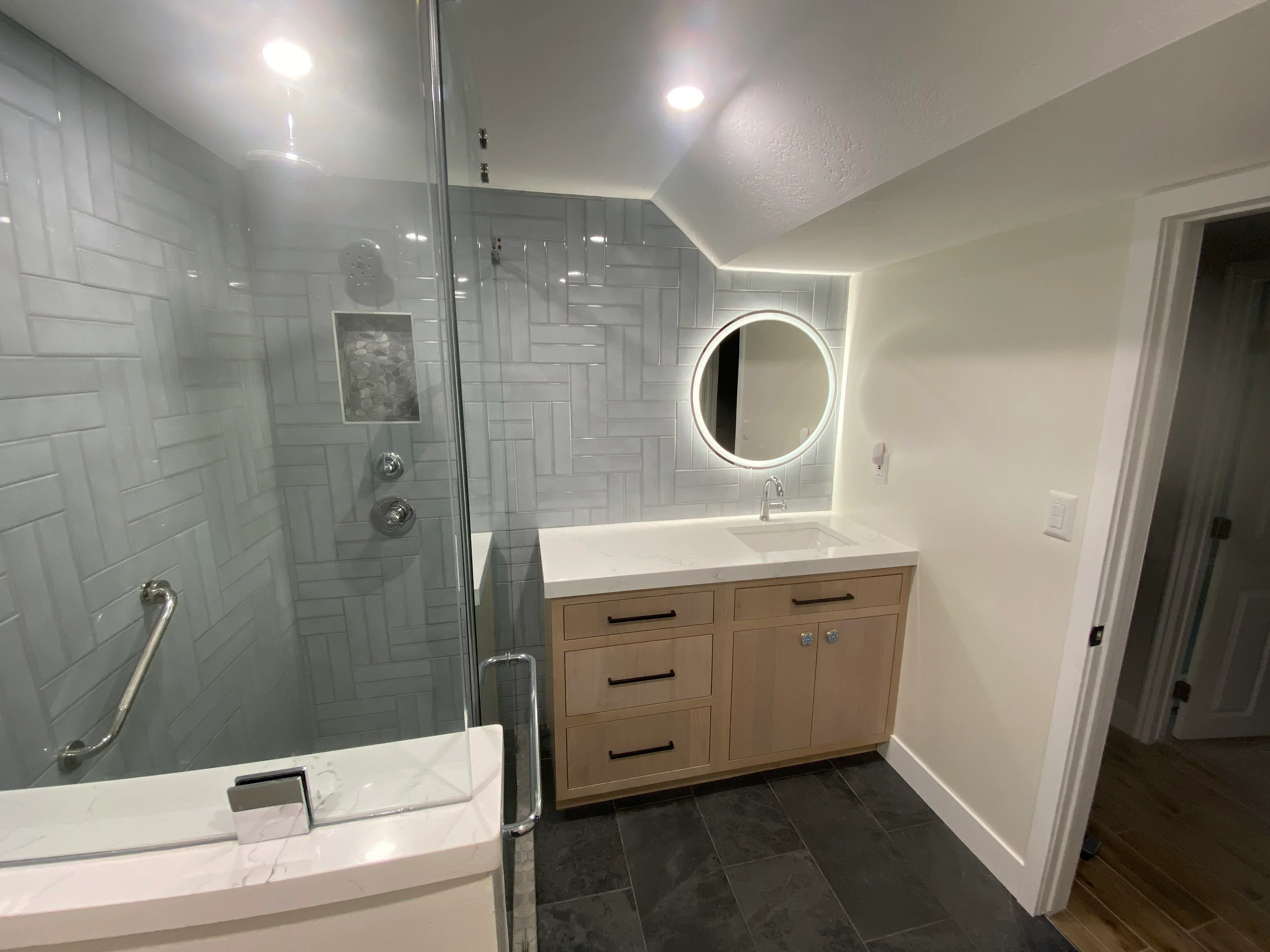 Modern bathroom with white subway tile shower, wood vanity, quartz countertop, and LED mirror