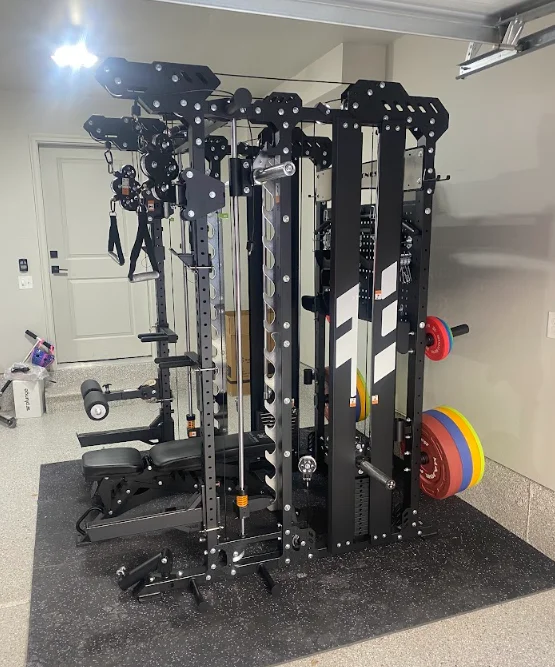Black steel multi-station gym frame with cable machines and weight plates on rubber flooring