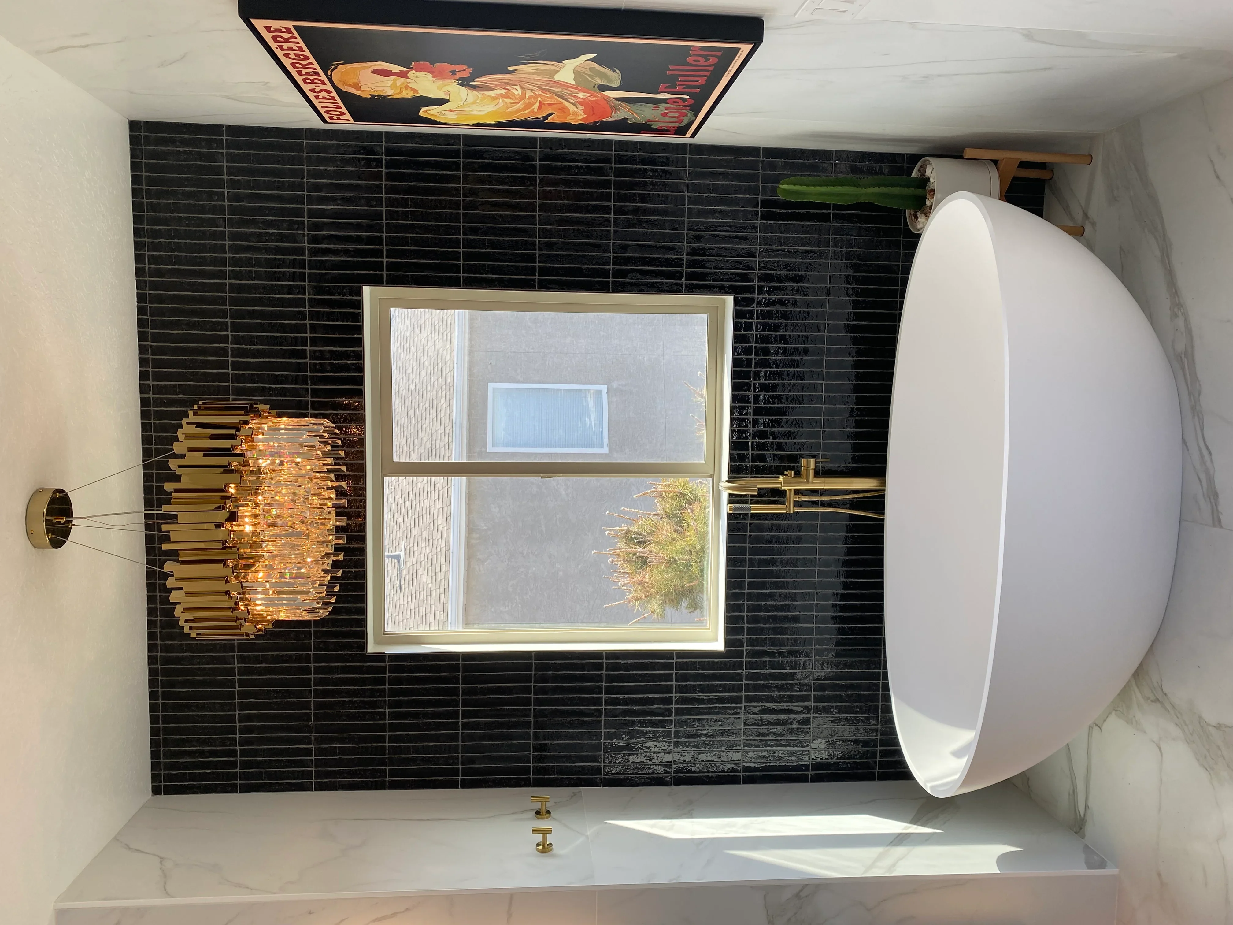Black subway tile bathroom walls with marble countertop and brass fixtures