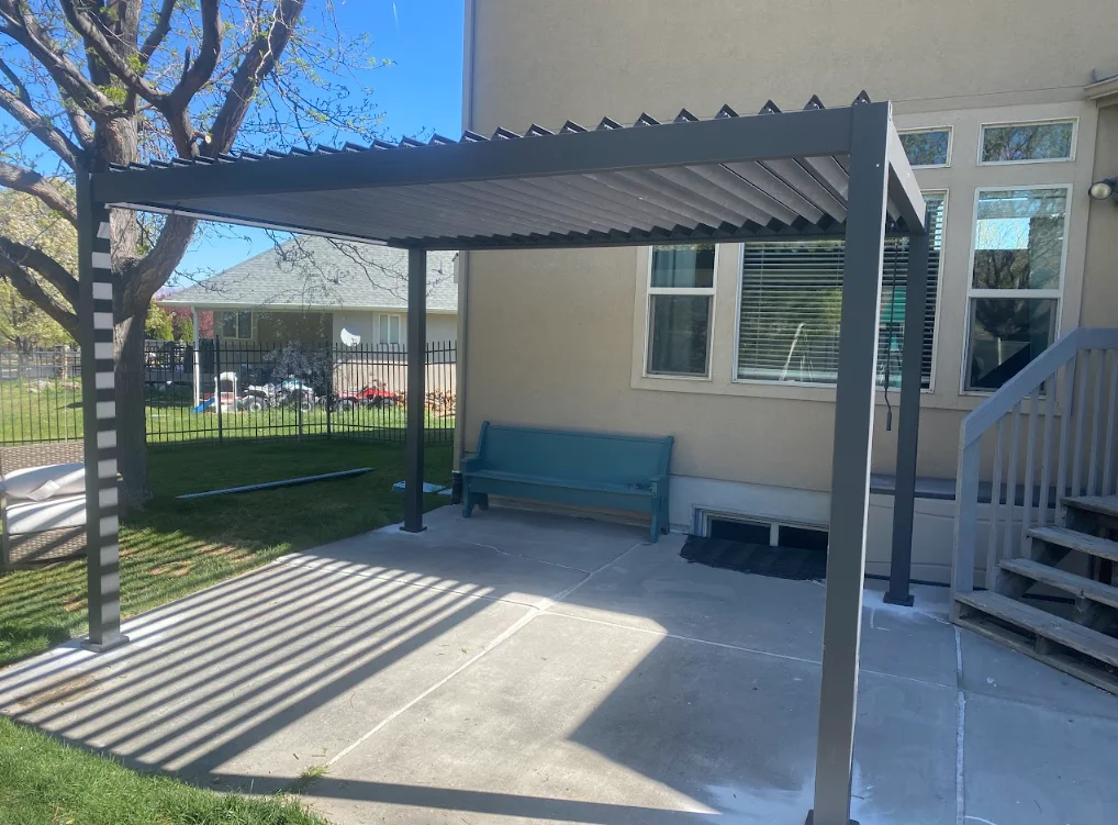Black aluminum pergola with louvered roof over concrete patio